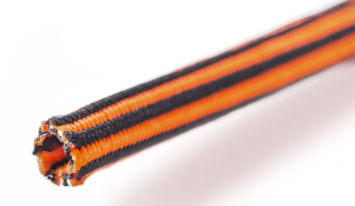 Eine Flechtschlauchlitze elastisch in Orange und Schwarz vor weißem Hintergrund als Nahaufnahme.