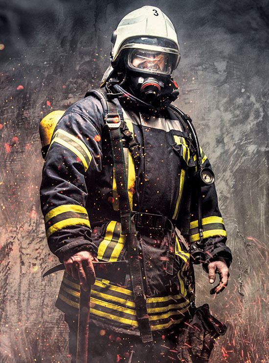 Ein Feuerwehrmann in voller Schutzausrüstung inklusive Atemschutzmaske, umgeben von Rauch und Funken