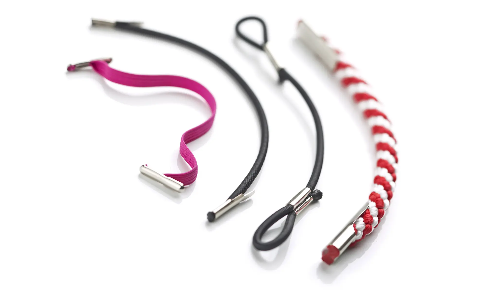 Produktfoto von unterschiedlichen, elastischen und geflochtenen Bändern und Kordeln, mit Befestigungselementen aus Metall, vor weißem Hintergrund