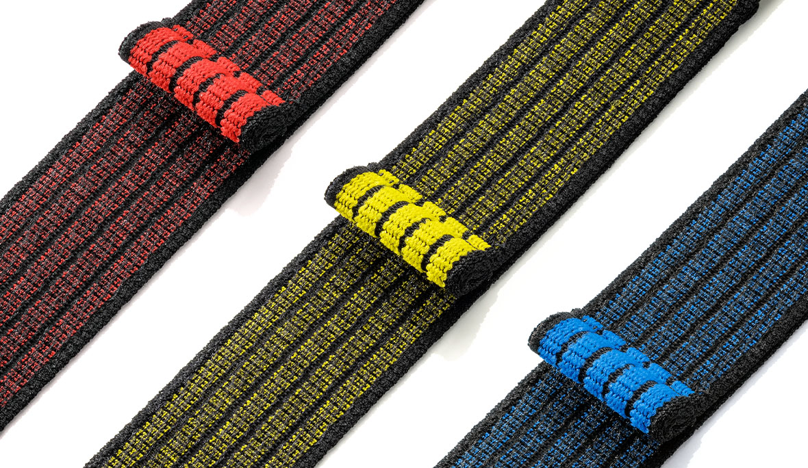 klettfähiger Elastikgürtel: Produktfoto mehrerer elastischer Klettgürtel, in schwarz-rot, in schwarz-gelb und in schwarzblau. Die Anordnung der Produkte vor weißem Hintergrund ist von rechts oben nach links unten.